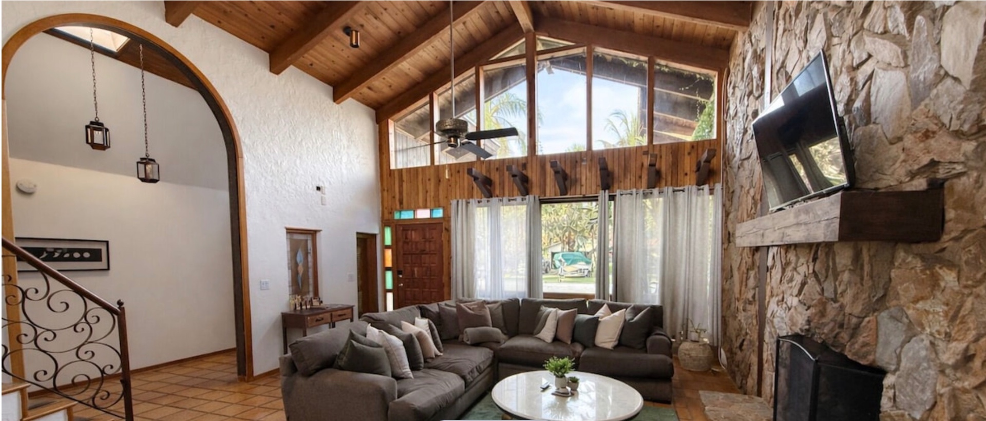 Living room with stone fireplace, sectional seating, and smart TV